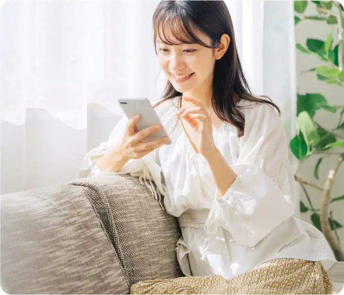 ソファに座ってスマートフォンをいじる女性