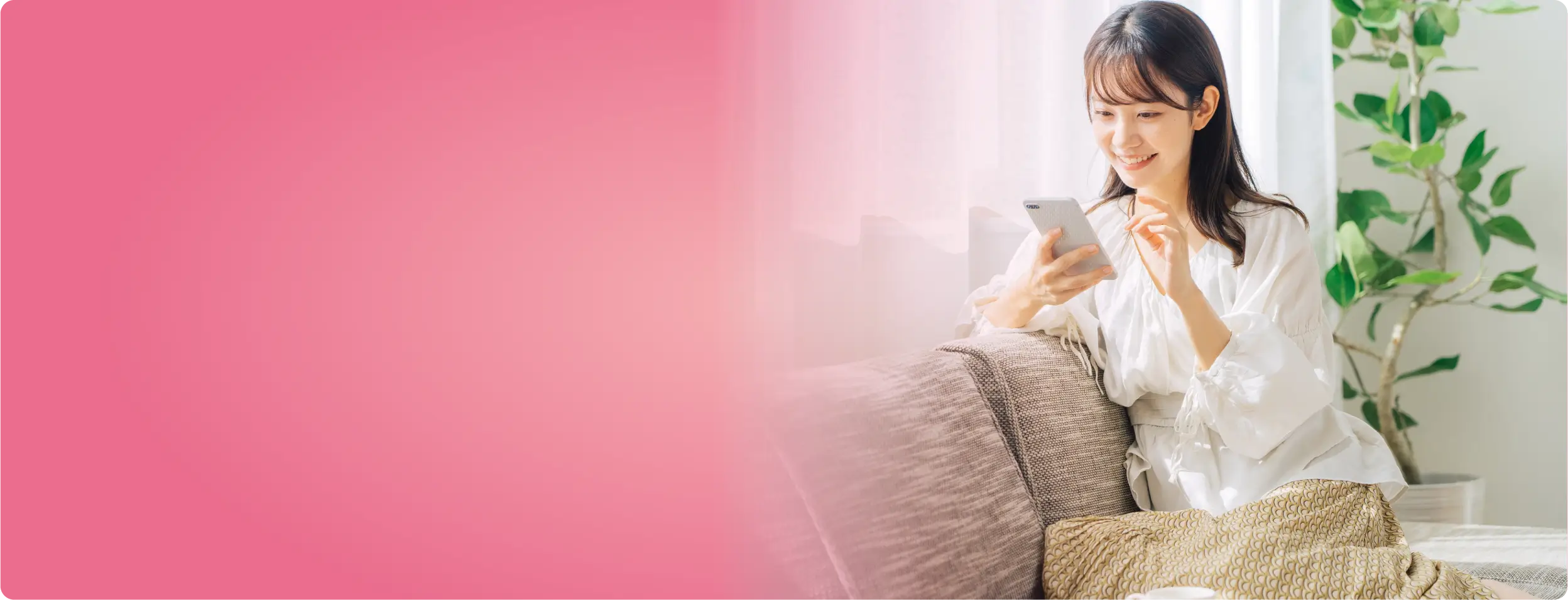 ソファに座ってスマートフォンをいじる女性